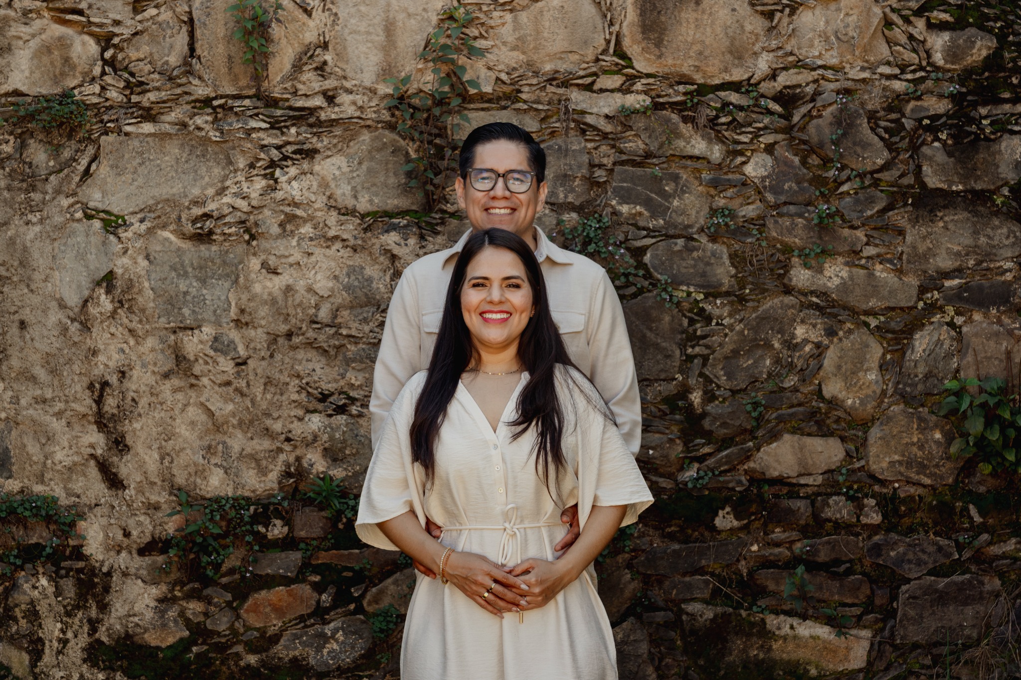 Rosa María y Joacim frente a un muro de piedra
